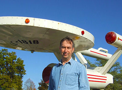 Stephen M. Miller beside a model of the star ship Enterprise