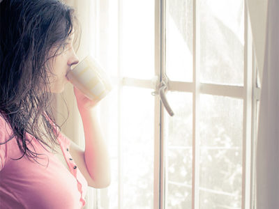 woman drinking coffee and looking out window