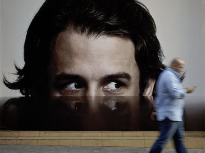 man walking in front of picture of man looking at him