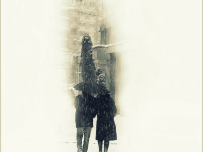 couple walking in the snow under and umbrella