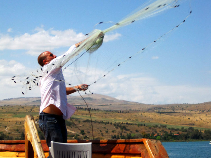 Man throwing fishing net from a boat