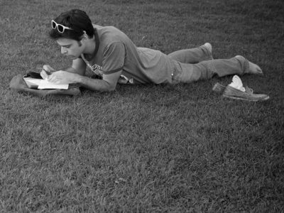 man lying on grass and writing