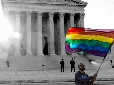 man waving a rainbow flag in front of the Supreme Court building