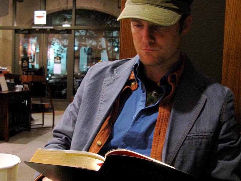 Man reading Bible in coffee shop