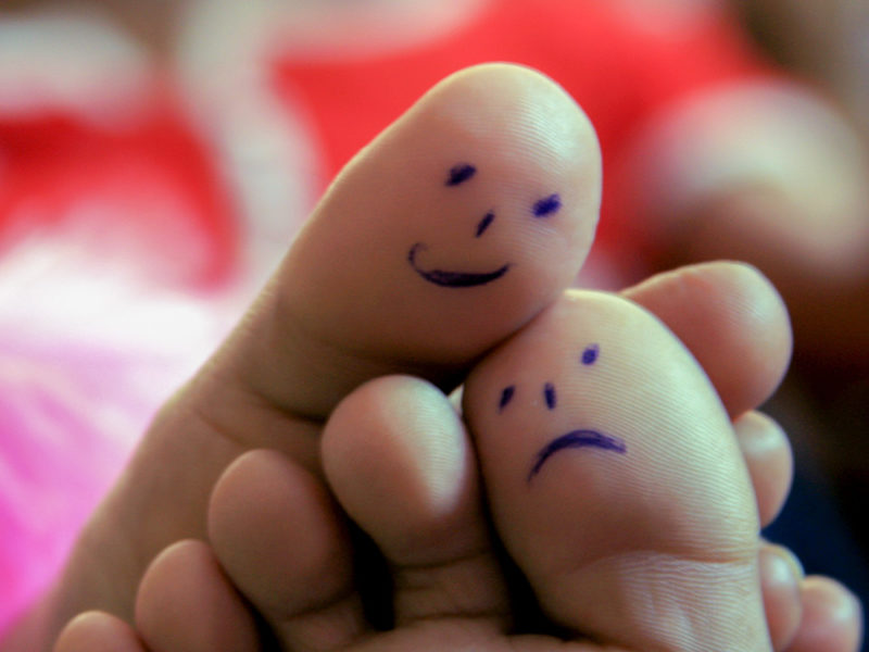 feet with happy face and sad face drawn on them
