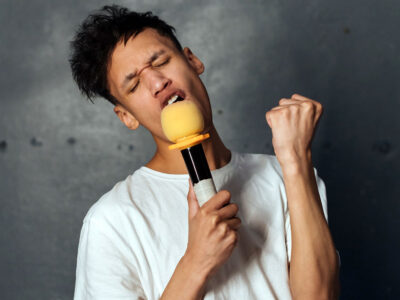 photo of young man singing into a microphone