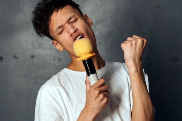 photo of young man singing into a microphone